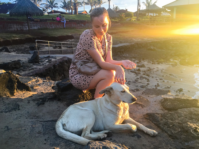 A woman sits with a stray dog on Easter Island.