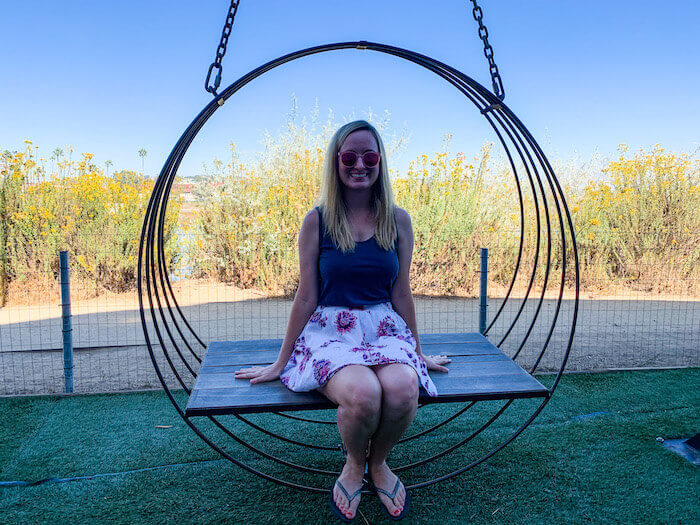 A woman is sitting on a swing outside of Viewpoint Brewing in Del Mar, California.