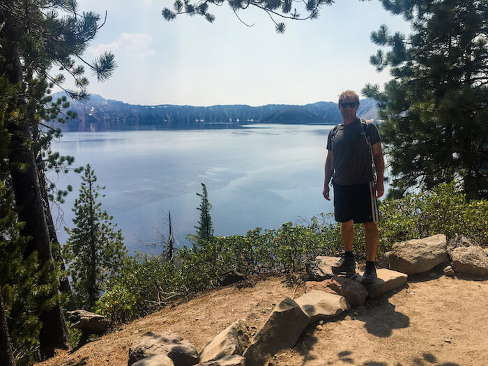 A man stands on a trail summit in Crater Lake National Park.