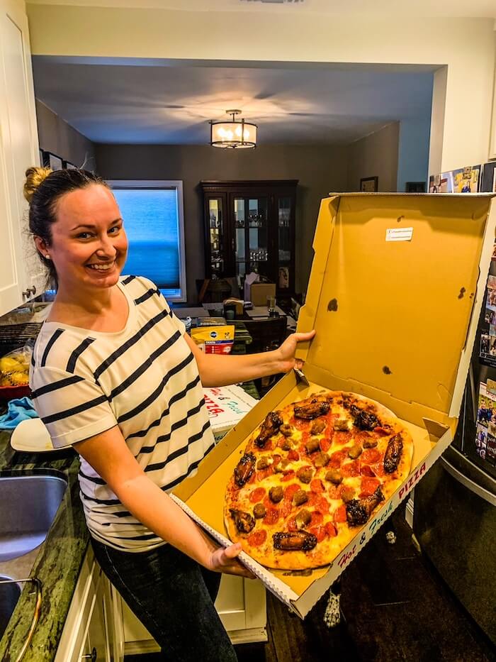 A woman with a box of pizza and chicken wings in San Diego.