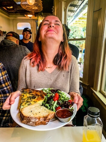 A woman happily eats lunch.