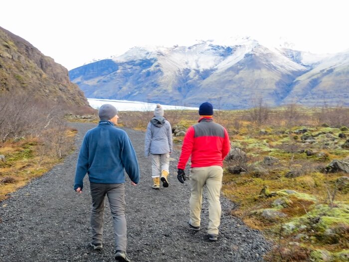 A group walks a path on an Iceland road trip.