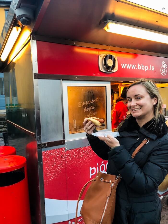 A woman eats a hot dog in Reykjavik.