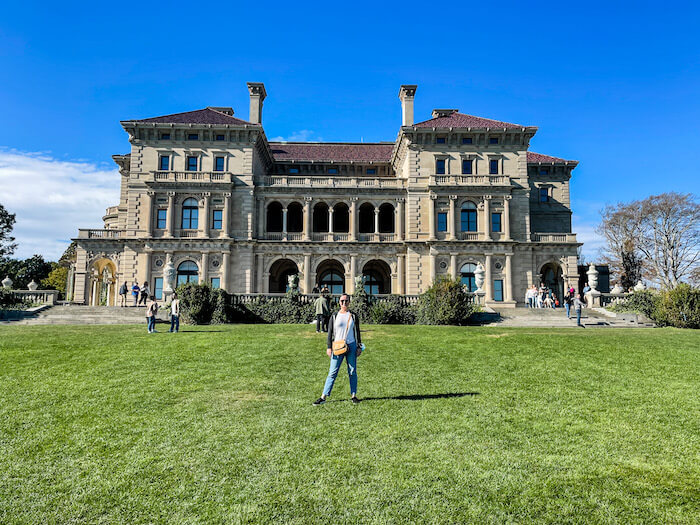 A woman stands in front of The Breakers, the biggest among mansions of Newport.