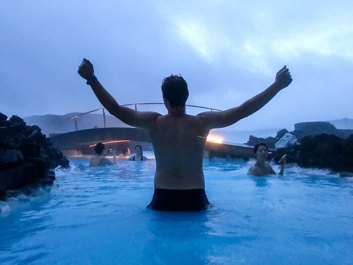 A man enjoys the water in the Blue Lagoon, his arms outstretched.