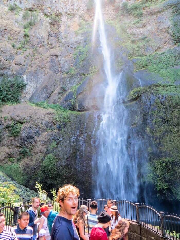 A man poses at a waterfall outside of Portland.
