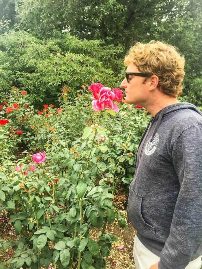 A man smells a rose in Washington Park in Portland.