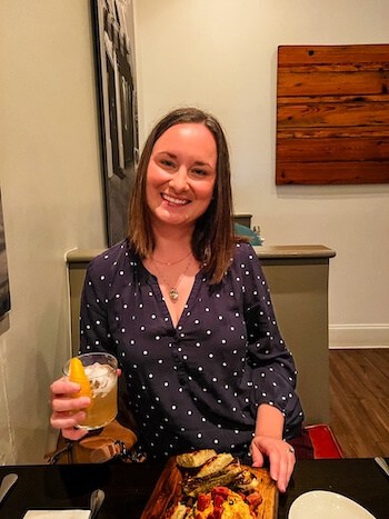 A woman poses with a cocktail at a restaurant.