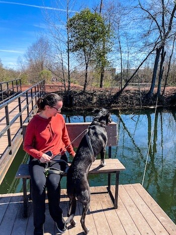A woman and her dog on a hike at a pond
