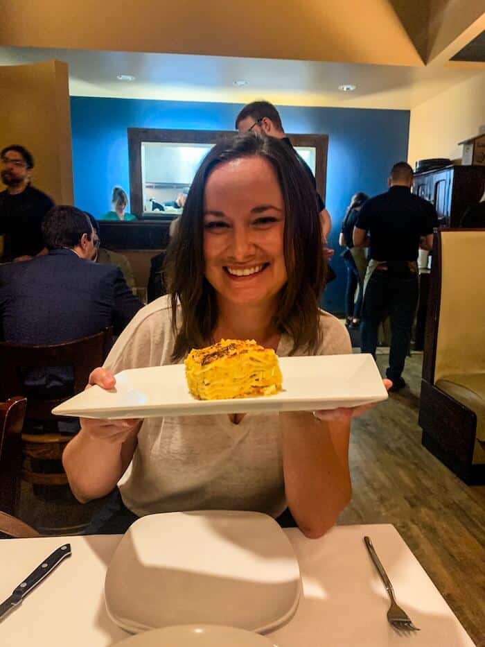 A woman holds a plate of mac 'n cheese.