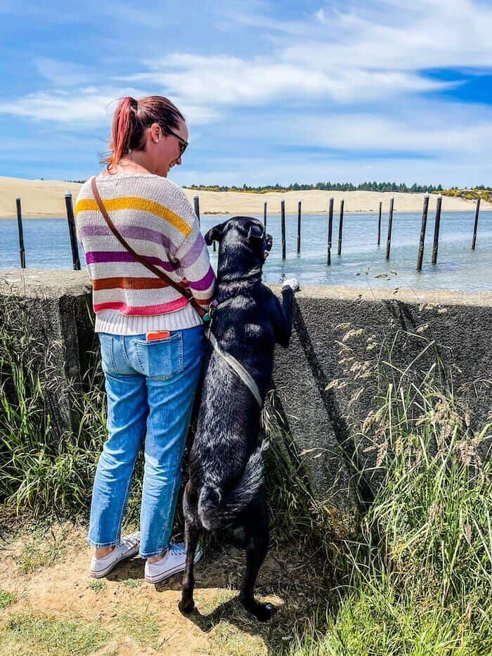 A woman poses with her dog after a hike.