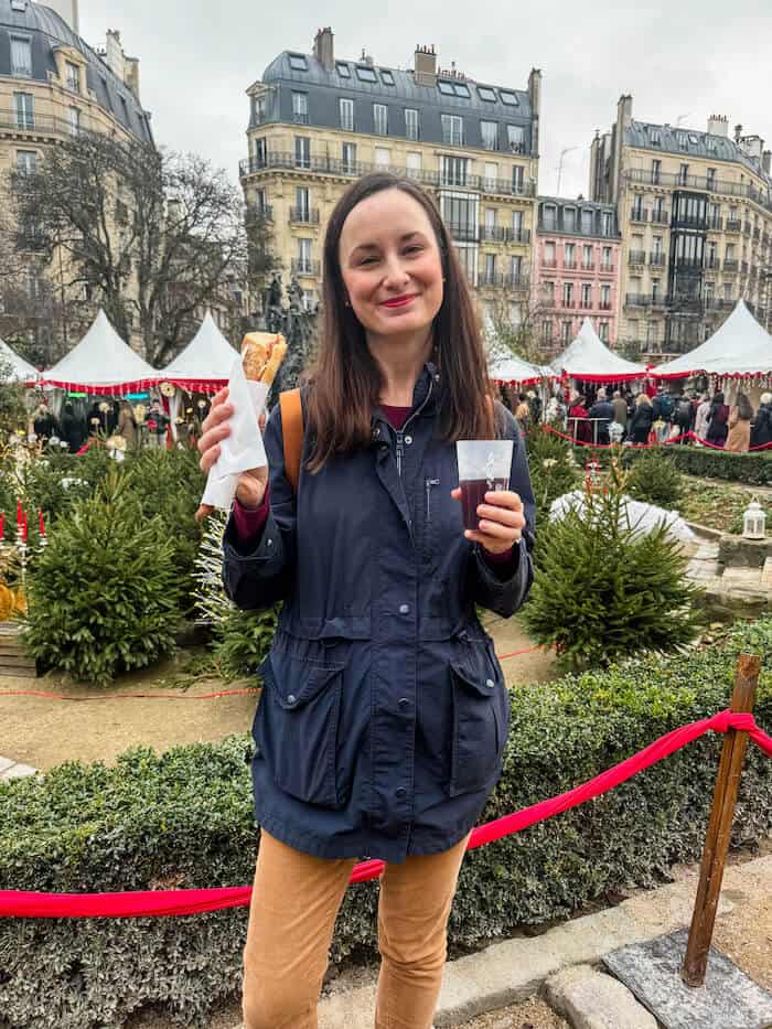 A woman eats savory treats at a Christmas market.