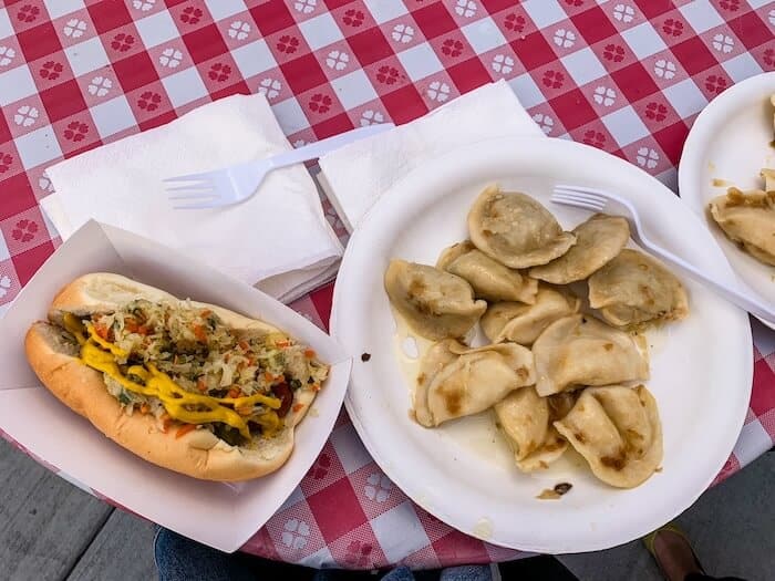 Platters of Polish food like pierogi and a sausage sandwich at a Polish festival in San Diego
