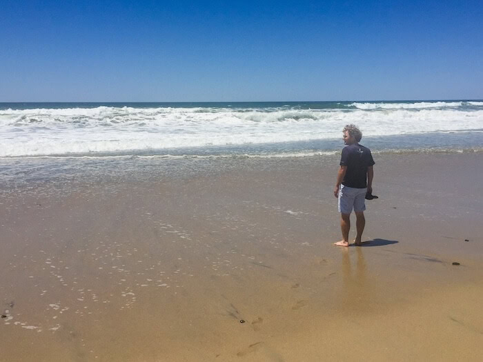 A man takes a walk on the beach in Carlsbad.