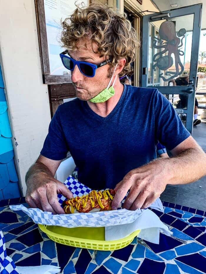 A man gets ready to eat a big sausage at Fathom Bistro, Bait, and Tackle in San Diego.
