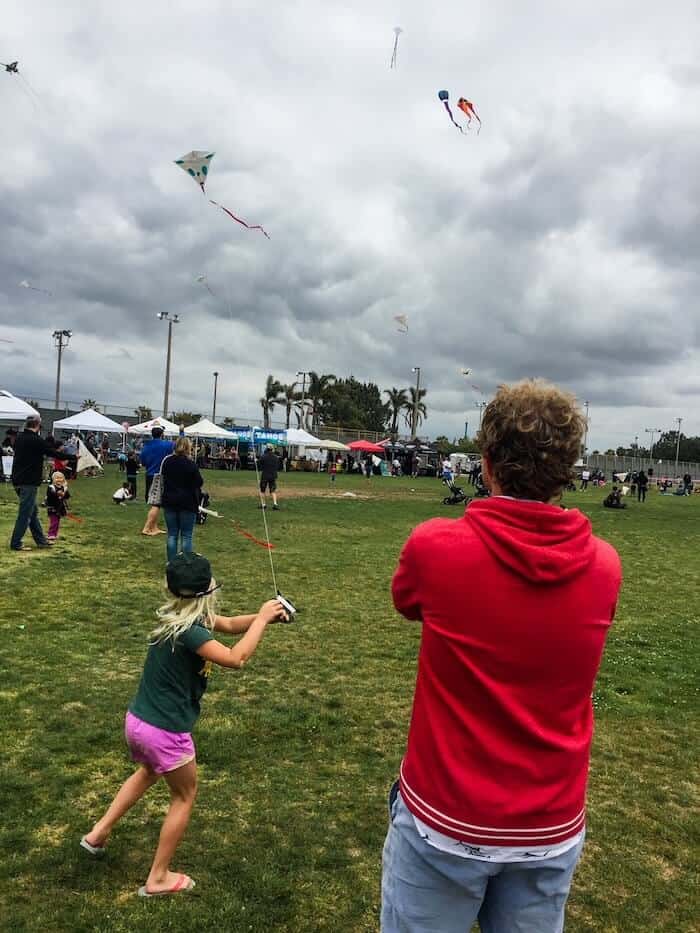 A man watches his niece fly a kite at the OB Kite Festival in San Diego, California.