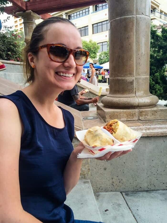 A woman poses with a breakfast burrito at the Little Italy Mercato in San Diego, California.