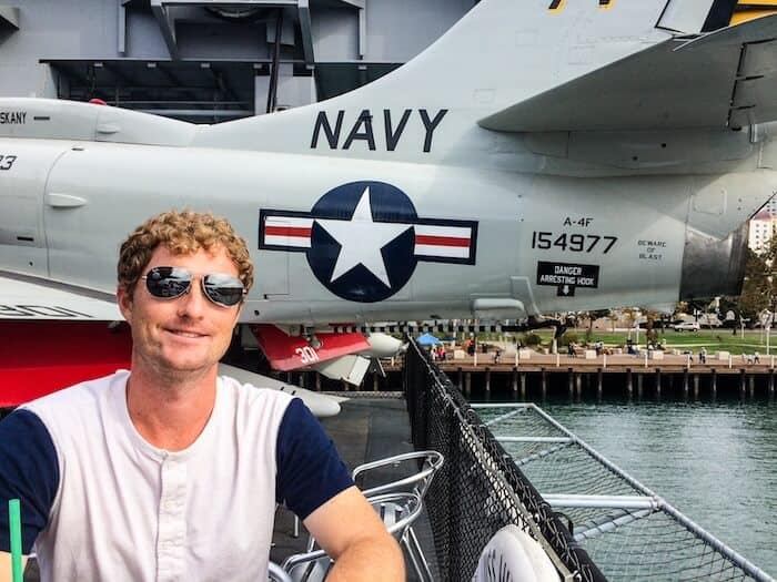 A man takes a break at the USS Midway Museum in San Diego, Califiornia, with a Navy plane behind him.