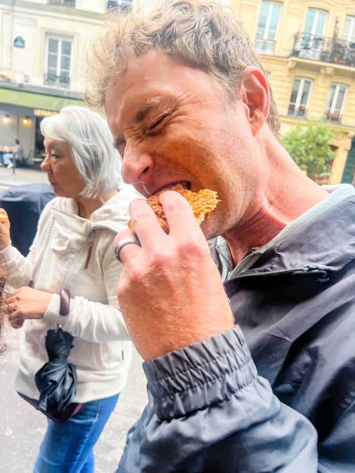 A man takes a bite of a French pastry.