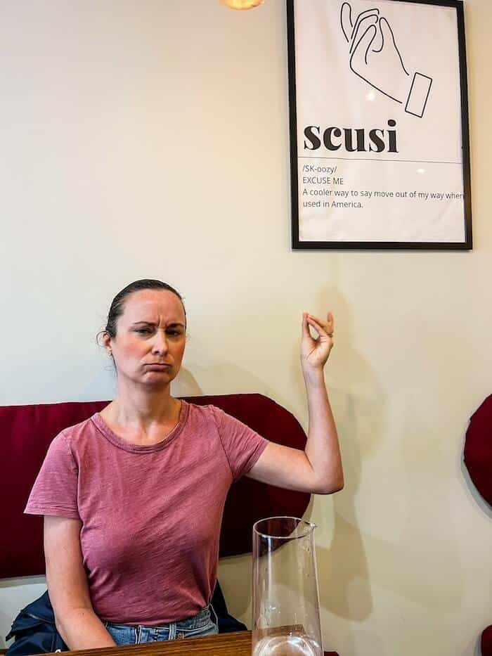 A woman poses with a sign in Italian.