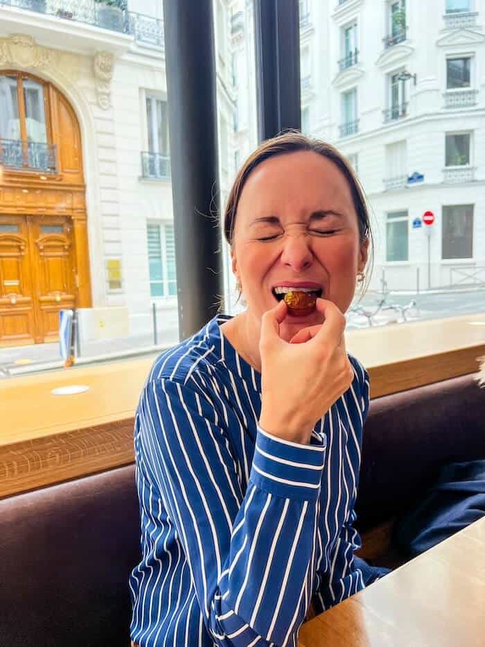 A woman takes a bite of a sweet treat.