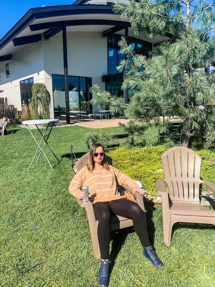 A woman relaxes at a brewery, beer in hand.