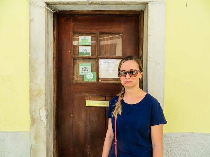A woman looks sad in front of a closed door.