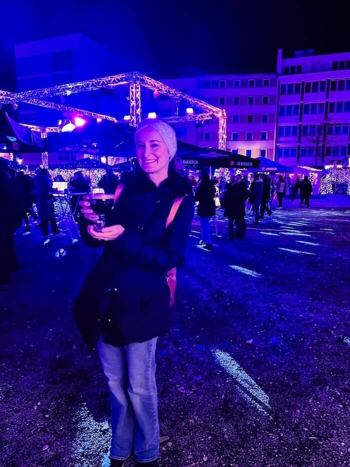 A woman poses with a beer at a holiday market in Germany.