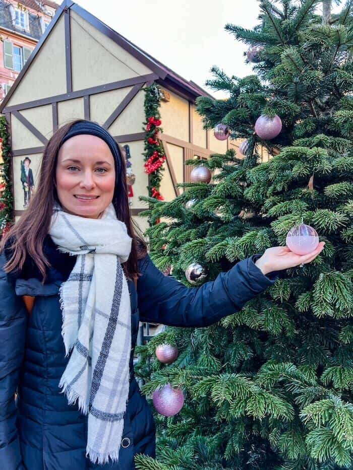A woman makes a face while posing with a Christmas tree.