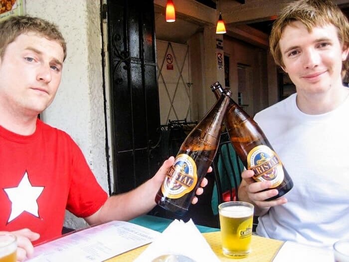 Two men clink beer bottles in Lima, Peru.