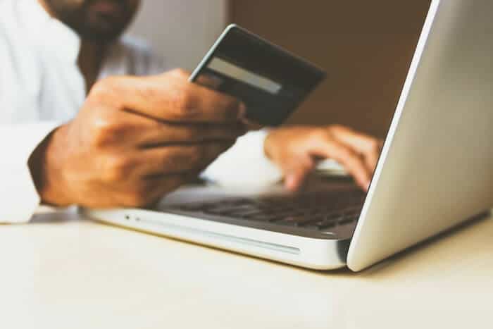 A man holds a credit card, getting ready to purchase something online.