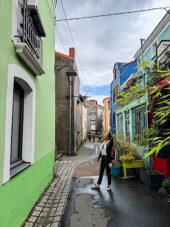 A woman poses against the colorful buildings of Trentemoult in Nantes.