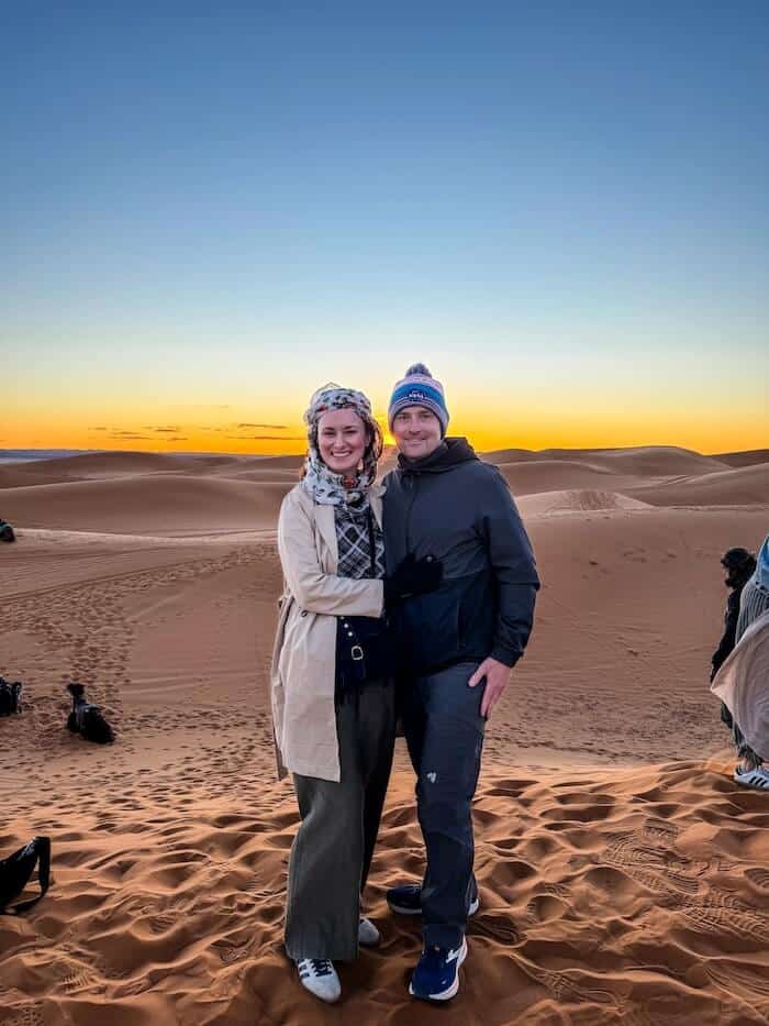A couple poses in the desert at sunrise.