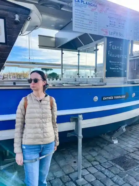 A woman stands in front of a seafood stand, disappointed because it's closed, in La Rochelle.