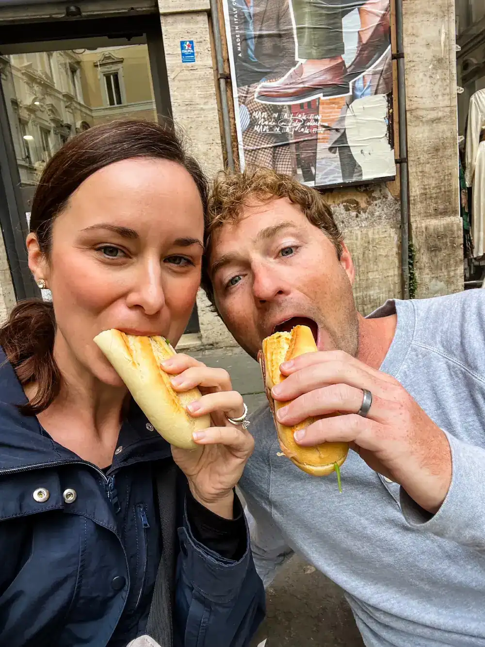 A couple eats baguette sandwiches in France.
