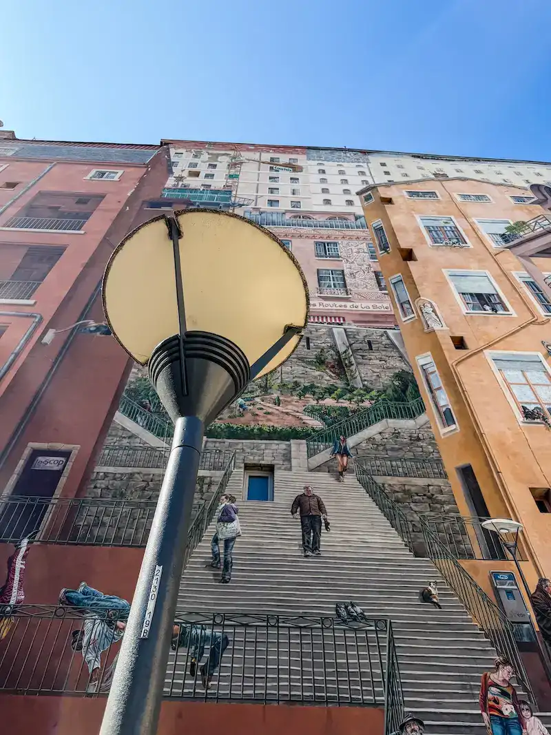 A lamp post against a large mural in Lyon