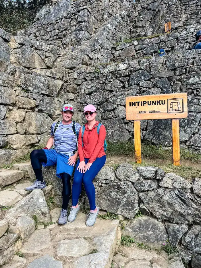 A couple poses near an altitude sign at Machu Picchu.