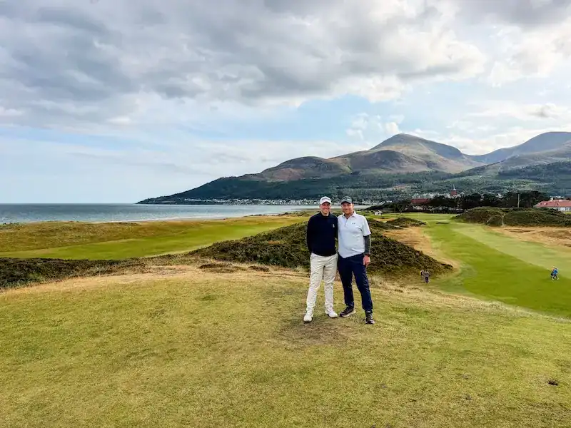 Two golfers pose on a golf course in Northern Ireland.