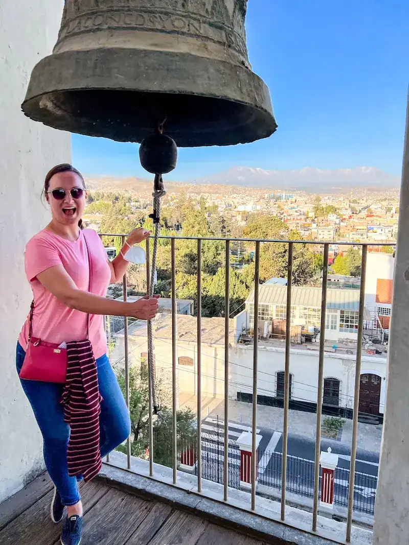 A woman rings a bell in a tower in Arequipa on a Peru itinerary.