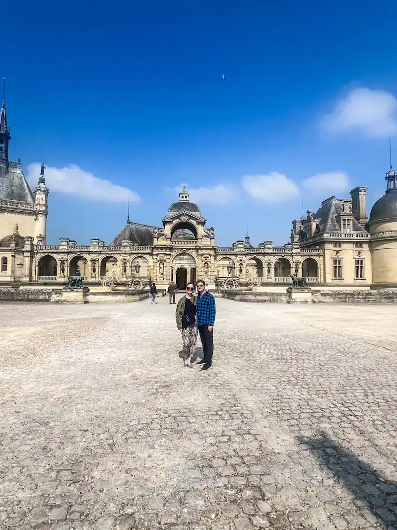 A couple poses in front of the castle in Chantilly near Paris.
