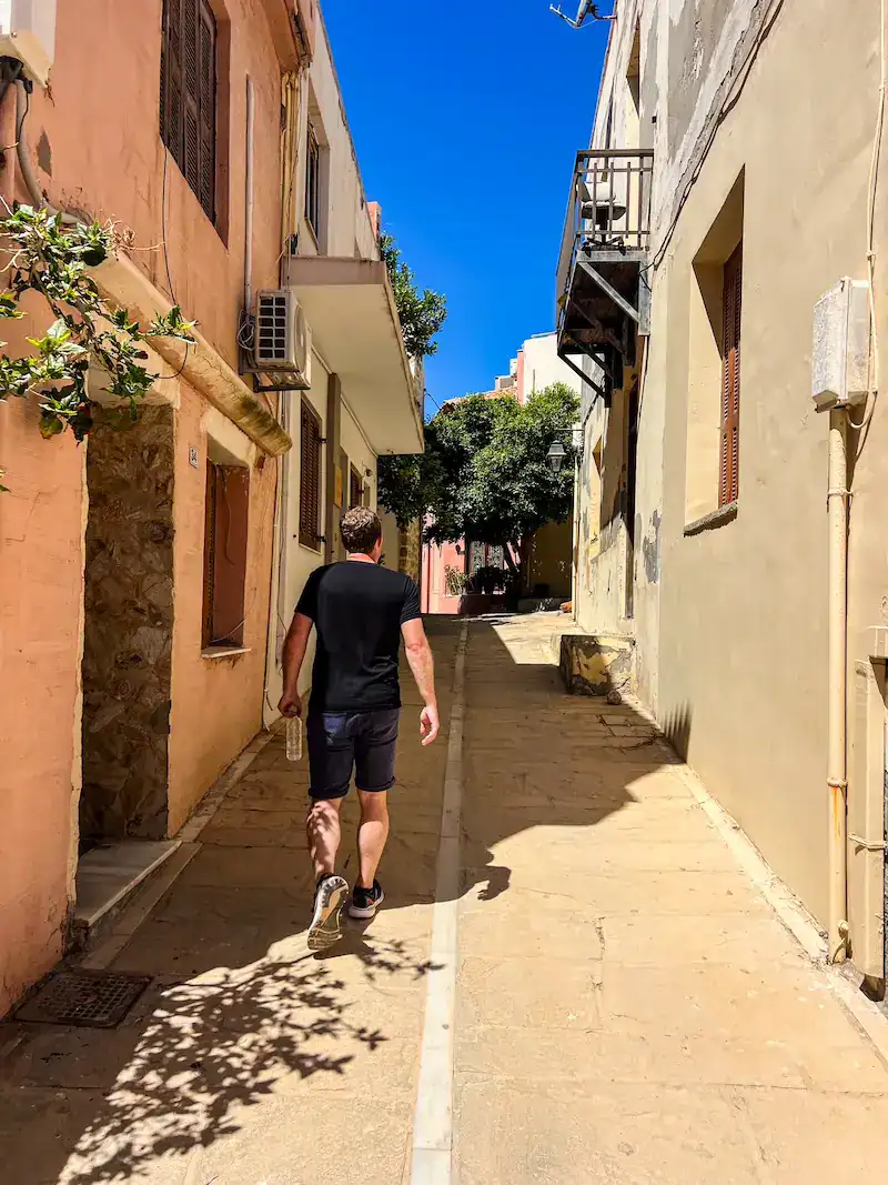 A man walking through a narrow alleyway on a Crete itinerary.