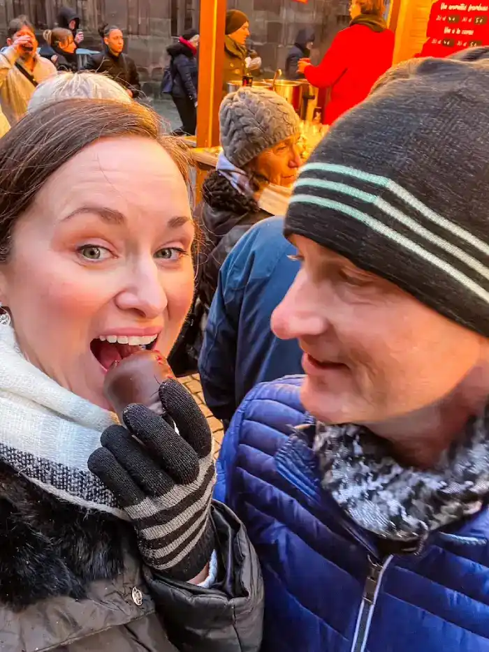 A couple shares a treat at a Christmas market in Strasbourg.